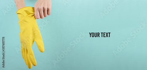 House cleaning concept. Female hands wear yellow rubber gloves for cleaning on a blue background with space for your text photo