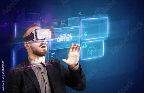 Businessman looking through Virtual Reality glasses with VIRTUAL MACHINE inscription, new technology concept