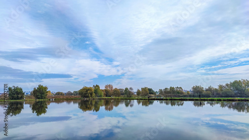 Sunny day on the perfect lake. Autumn lake with reflection on the water. Cloudy sky in the sunny day. © thaarey1986