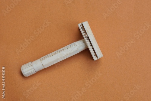one old gray bakelite razor lies on a brown table
