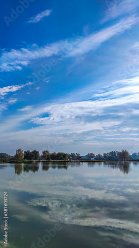 Sunny day on the perfect lake. Autumn lake with reflection on the water. Cloudy sky in the sunny day. © zyoma_1986