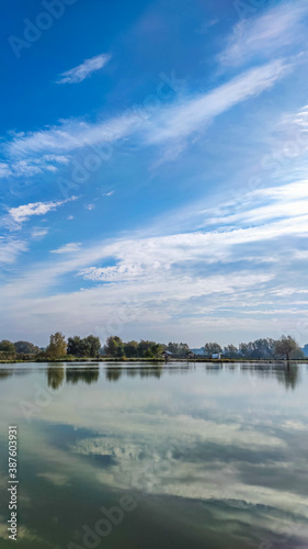 Sunny day on the perfect lake. Autumn lake with reflection on the water. Cloudy sky in the sunny day.