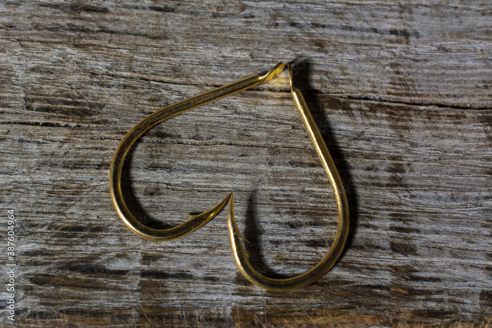 Fishing hooks set in the shape of a heart on a wooden background.