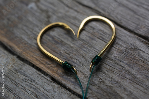 Fishing hooks set in the shape of a heart on a wooden background.