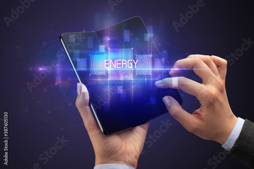 Businessman holding a foldable smartphone with ENERGY inscription, new technology concept