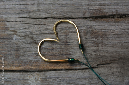 Fishing hooks set in the shape of a heart on a wooden background.