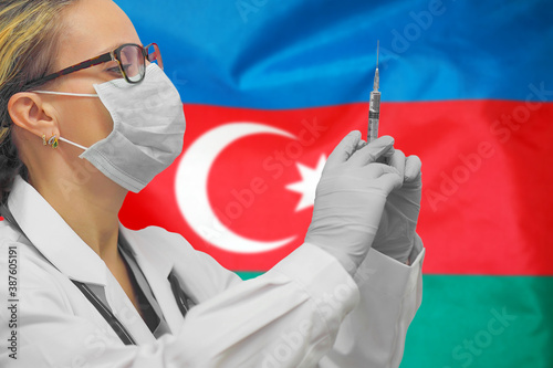 Female doctor or nurse in gloves holding syringe for vaccination against the background of the Azerbaijan flag. Medicine concept and fight the virus. Coronavirus in Azerbaijan