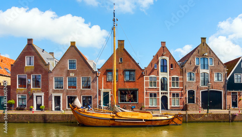 Monnickendam centre with a frontal view of tradional dutch houses and a frisian skutsje (dutch barge) at the Gooische Kaai street. North Holland, The Netherlands.