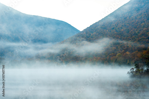 Early morning fog rising above calm lake in the White Mountains of NH. photo