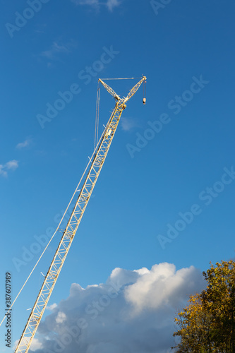 high yellow construction crane on a background of blue sky and white clouds