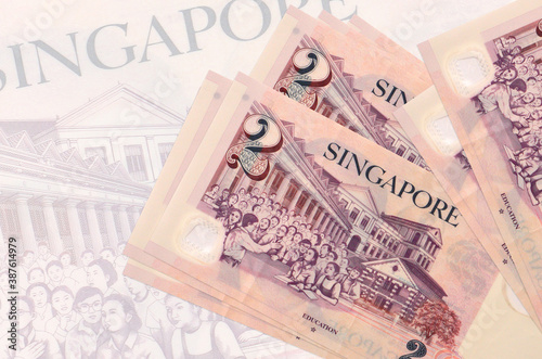 2 Singaporean dollars bills lies in stack on background of big semi-transparent banknote. Abstract presentation of national currency photo