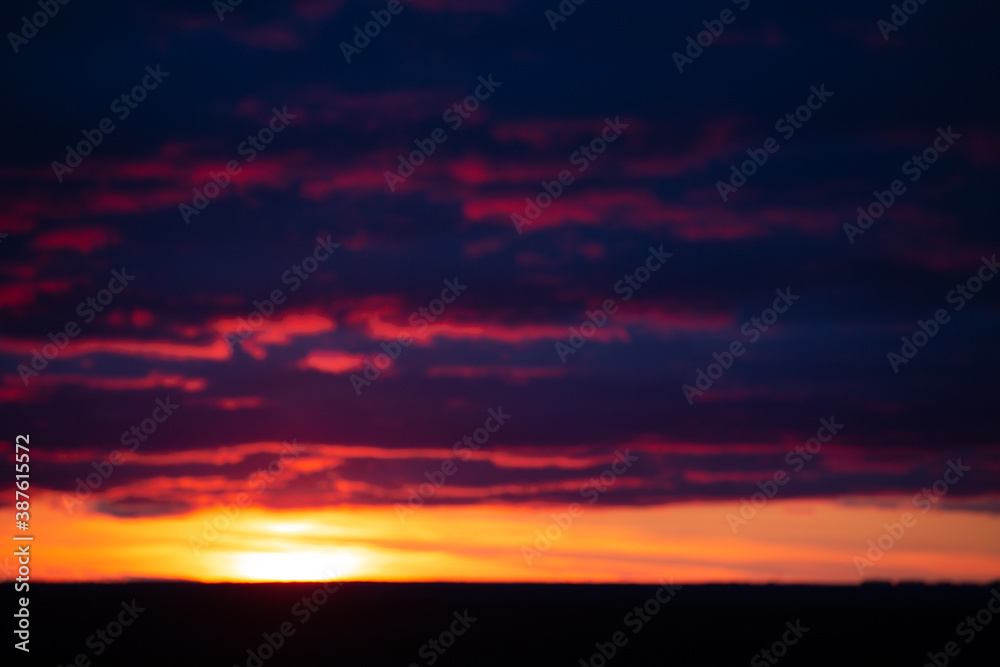 Orange-purple dramatic clouds lit by the setting sun against the evening sky. Blurred evening sky. Abstract background.