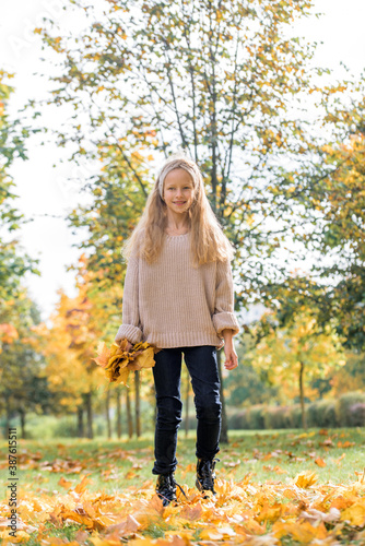 Beautiful little girl jumping with autumn leaves in the park outdoor. leaf fall  lifestyle.