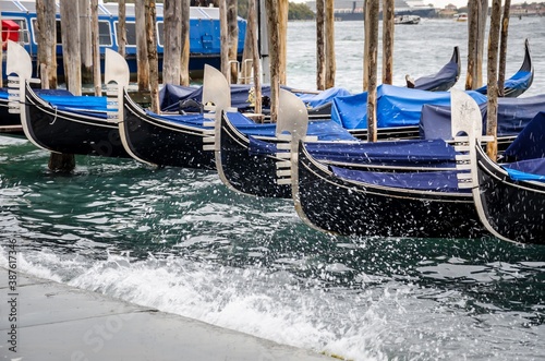 Gondolas moored by Saint Mark square with San Giorgio di Maggiore church background at sunset in Venice, Italy.