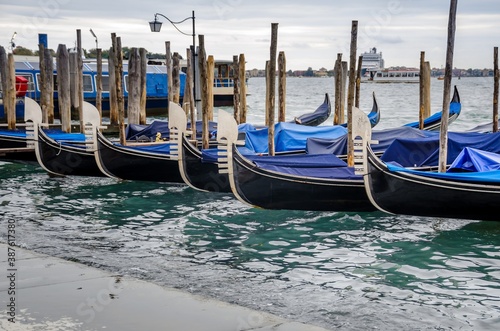 Gondolas moored by Saint Mark square with San Giorgio di Maggiore church background at sunset in Venice, Italy.