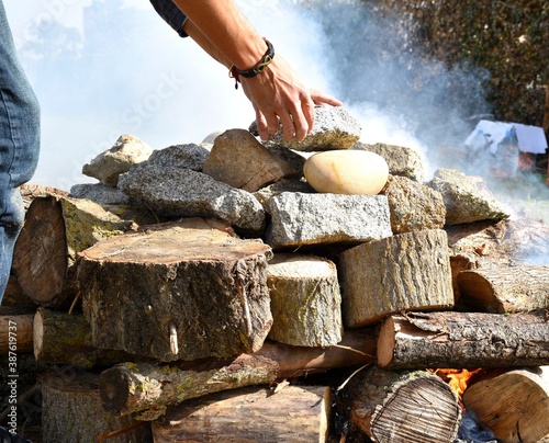 Hands leaving stones called grandmothers on the firewood for the temazcal.