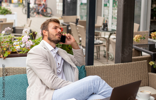 Businessman is working and talking on his phone in the coffee bar 