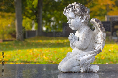 Sculpture of a little angel on a tomb in cemetery. Selective focus