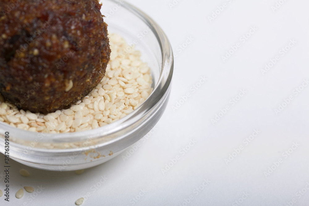 Dried fruit and nuts candy. Made at home in isolation during the epidemic. Lies on white sesame seeds. Dried fruit and nuts candy. Made at home in isolation during the epidemic. Lies on white sesame seeds.