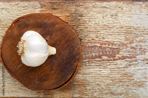 on a wooden table on a wooden stand a head of garlic.