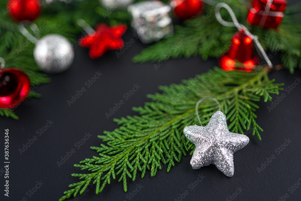Christmas composition with silver star on the fir tree. Black Blurred focus background with gift and red toys. Winter holiday theme. Space for text. Christmas composition with silver star on the fir tree. Black Blurred focus background with gift and red toys. Winter holiday theme. Space for text.