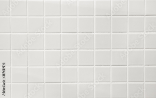 White ceramic squares with white filler on bathroom wall. Background.