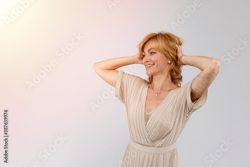 Close up portrait of a middle aged woman standing with hands behind head isolated on white background