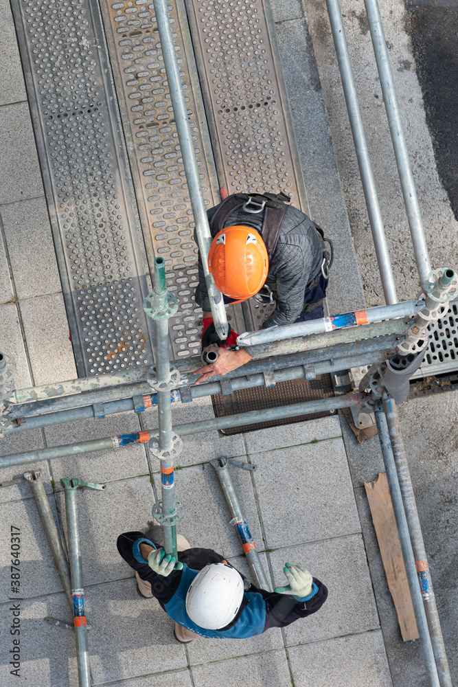 obreros de la construcción colocando andamios de obra para una  rehabilitación de una fachada Stock Photo