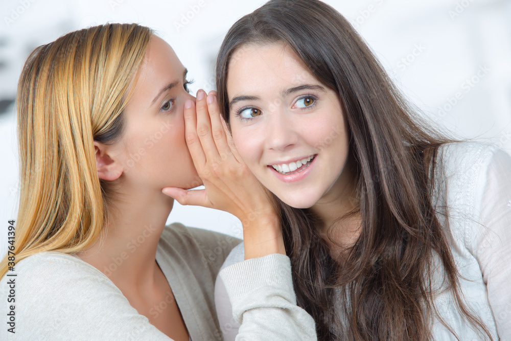 one friend is whispering a secret to the other one friend is whispering a secret to the other