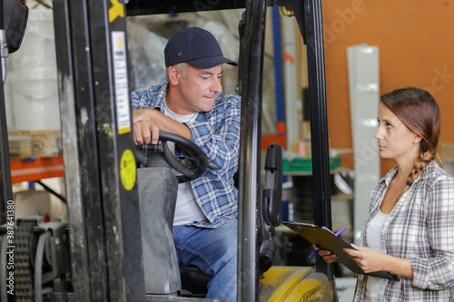 forklift driver talking with his manager in a large warehouse