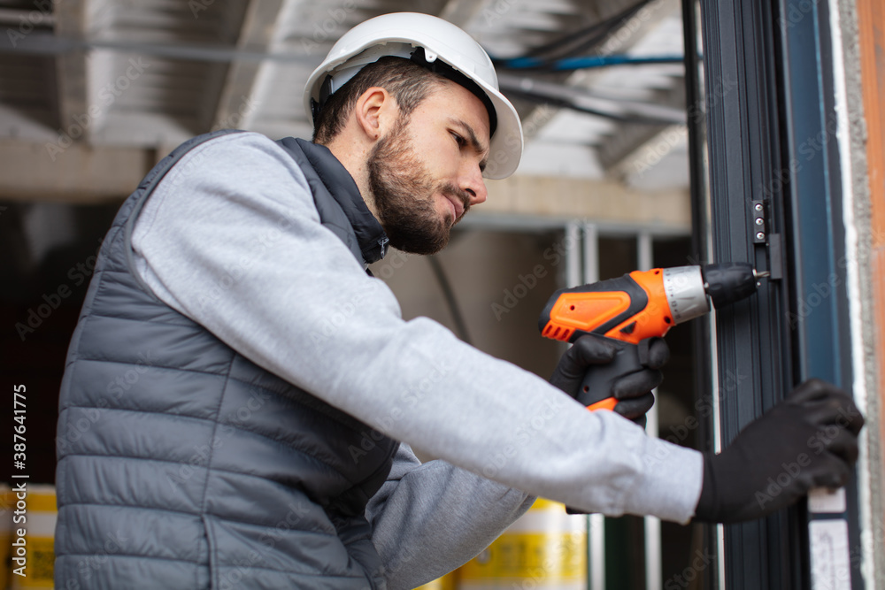 handsome young man installing bay window in a new house handsome young man installing bay window in a new house