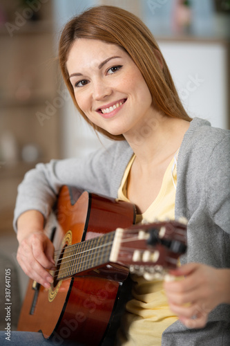a beautiful woman smile while playing acoustic guitar