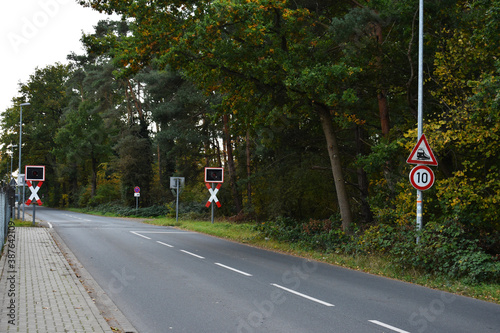 train railroad crossing sign on the road with speed limit and red light in forest urban 