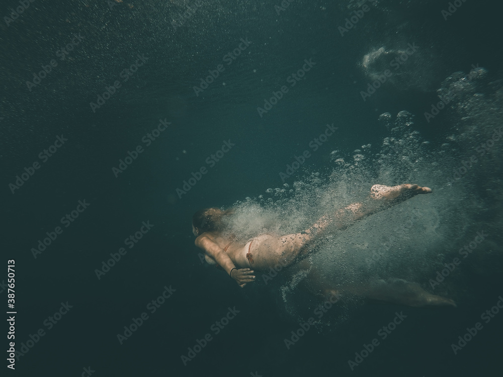 European young woman diving and swimming underwater in Croatia in mediterranean sea
