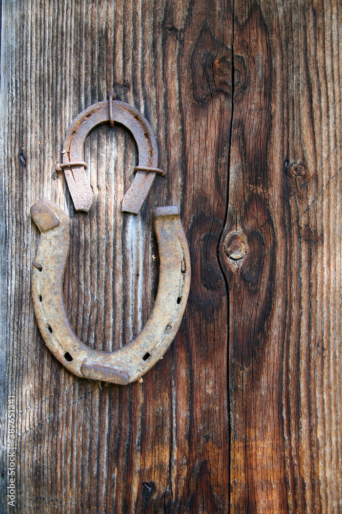 Two horseshoes nailed onto rustic wooden door as a lucky charm Two horseshoes nailed onto rustic wooden door as a lucky charm