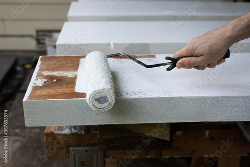 Male Hand Painting Wood Boards with White Paint and Paint Roller