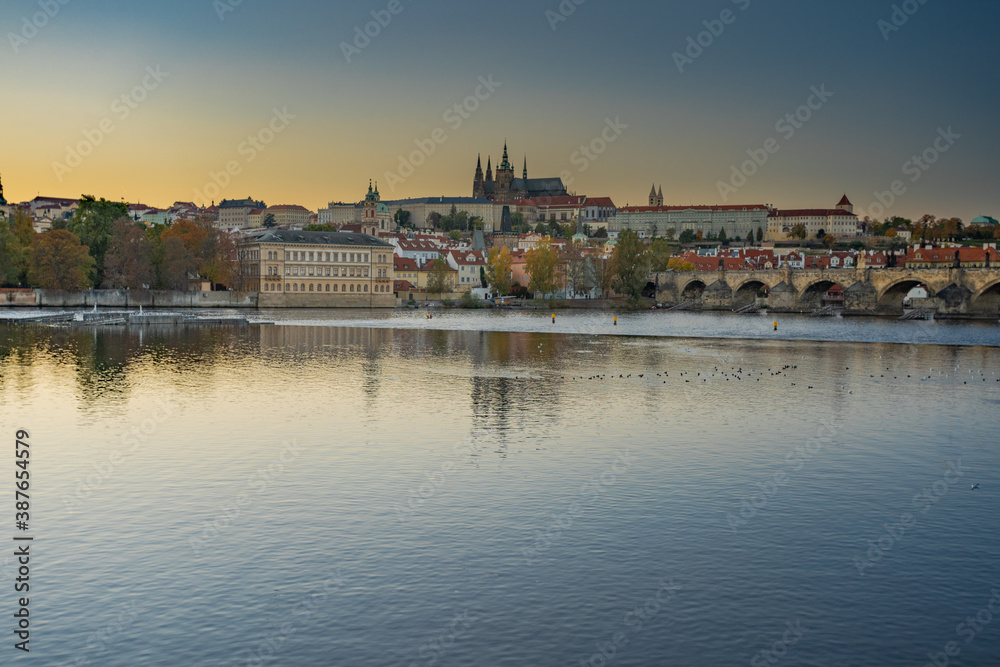 beautiful view of the sights of Prague Castle and St. Vitus Cathedral and Charles Bridge and the level of the Vltava River in the center of Prague at sunset. the sun colors the sky orange