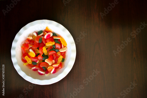 bowl of bright coloured lollies candy on wood board