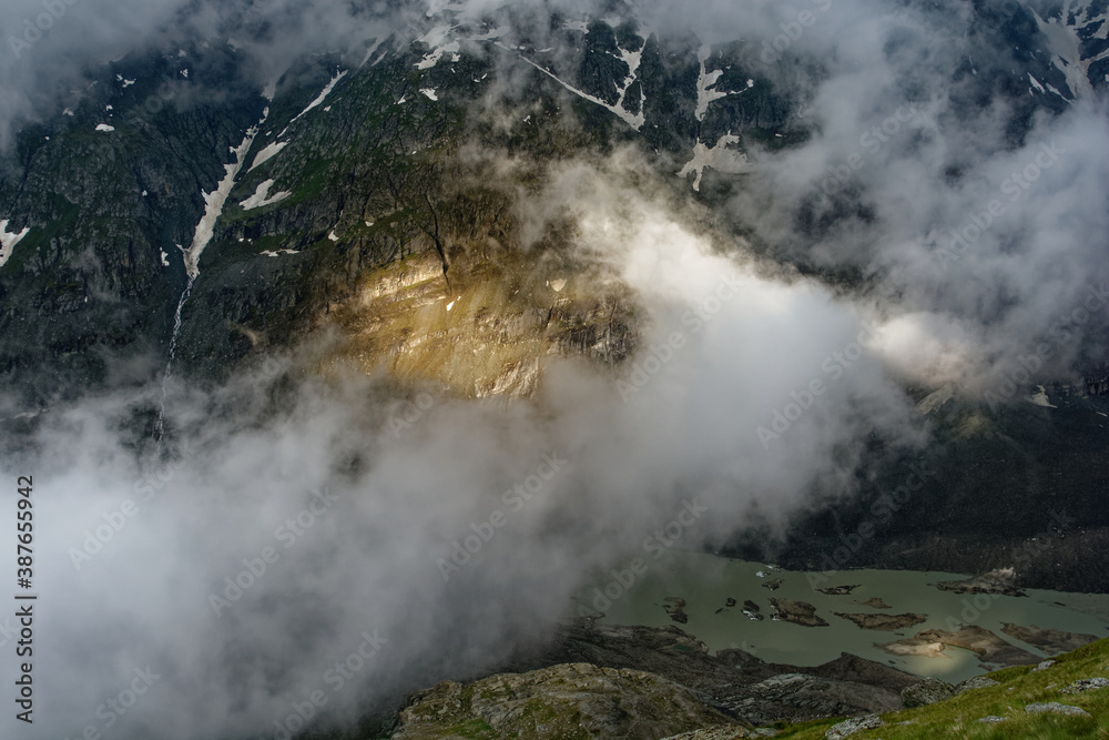 Clouds and fog in the Alps, the highest mountains in Europe. Austria or Italy in autumn, bad weather and rocks in cold windy day
