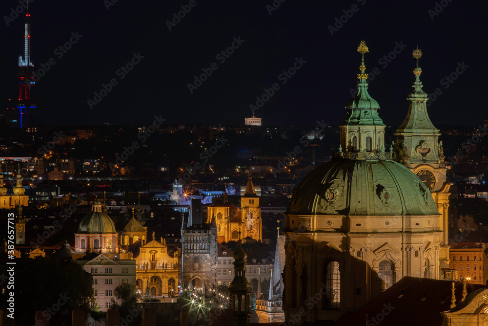 
The tower of the Church of St. Nicholas is a Baroque church located in Prague from 1625 in the center of Prague. in the background a view of street lights in the city at night