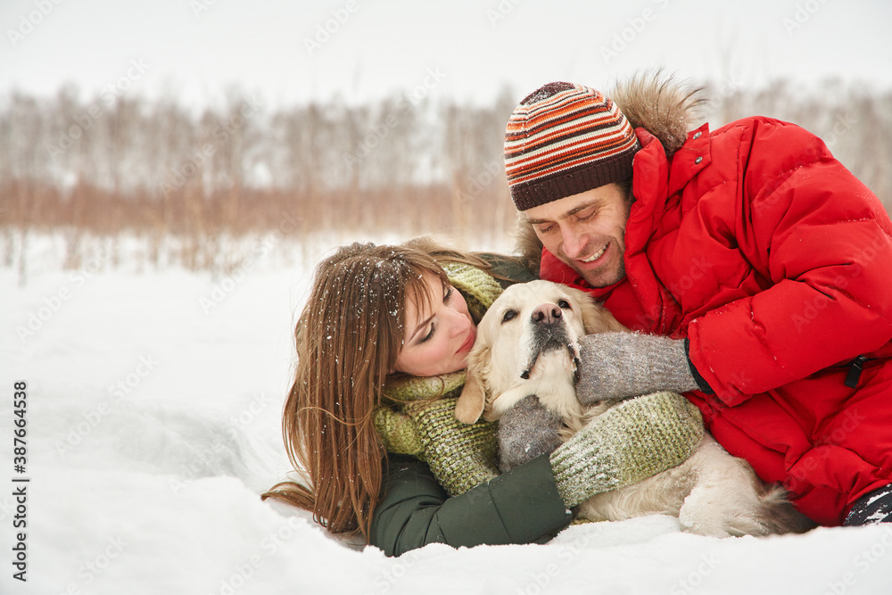 portrait of a young couple with a dog on a winter walk. man and woman with labrador portrait of a young couple with a dog on a winter walk. man and woman with labrador