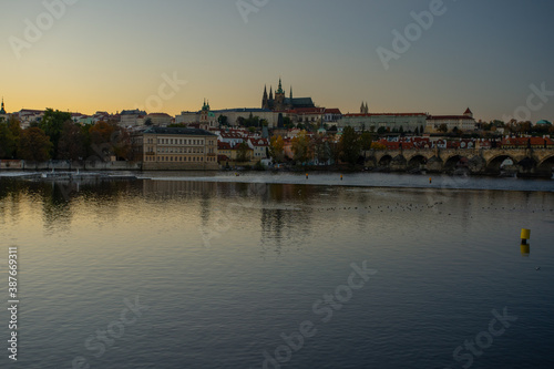 view of the Vltava river and Prague Castle St. Vitus Cathedral and Charles Bridge in the center of Prague at sunset. there are reflections on the river surface and the sky is illuminated by the sun © svetjekolem