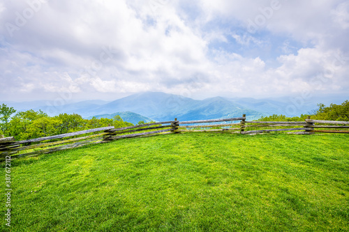 Devil's Knob Overlook with wooden fence and green grass field meadow at Wintergreen resort town village in Blue Ridge mountains in summer clouds mist fog