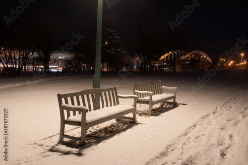 雪に覆われた冬の夜の公園のベンチ 
