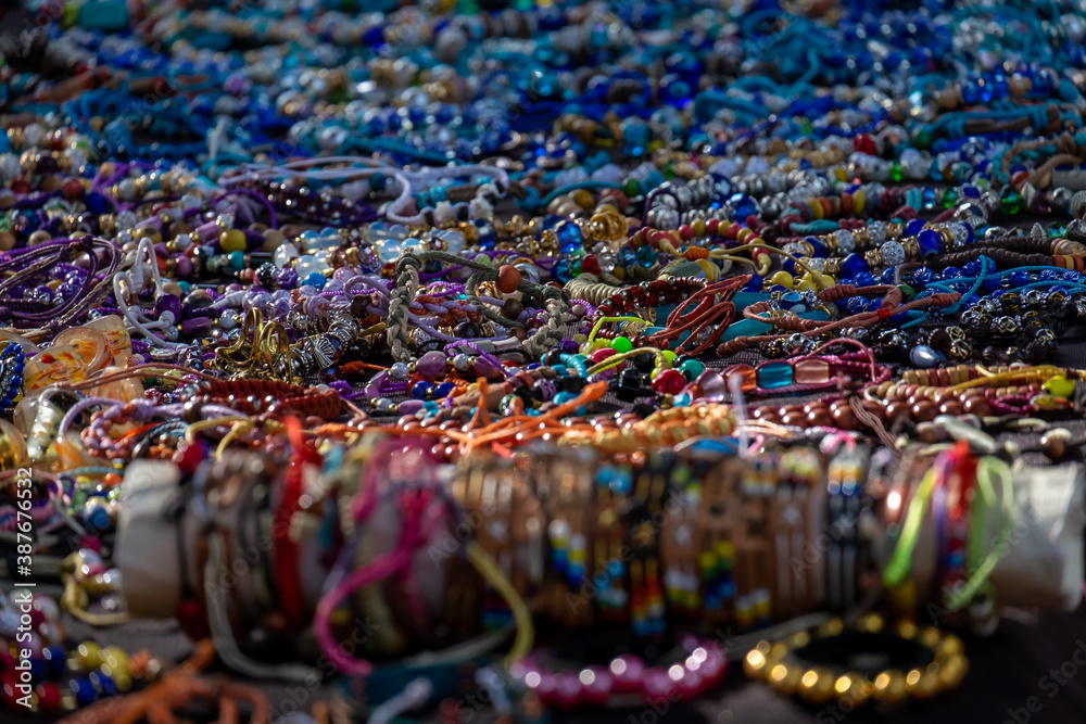 Fototapeta premium A table of decorative colorful cosmetic beads of luxury objects. The glamour balls, plastic jewelry, fashionable necklaces, and bracelets at a bazaar. The trinkets are of multiple colors.