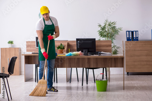 Young male contractor cleaning the office © Elnur