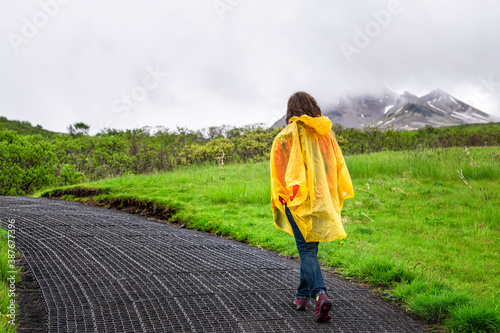 Fotografia Skaftafell, Iceland green summer landscape and woman in yellow poncho walking hi