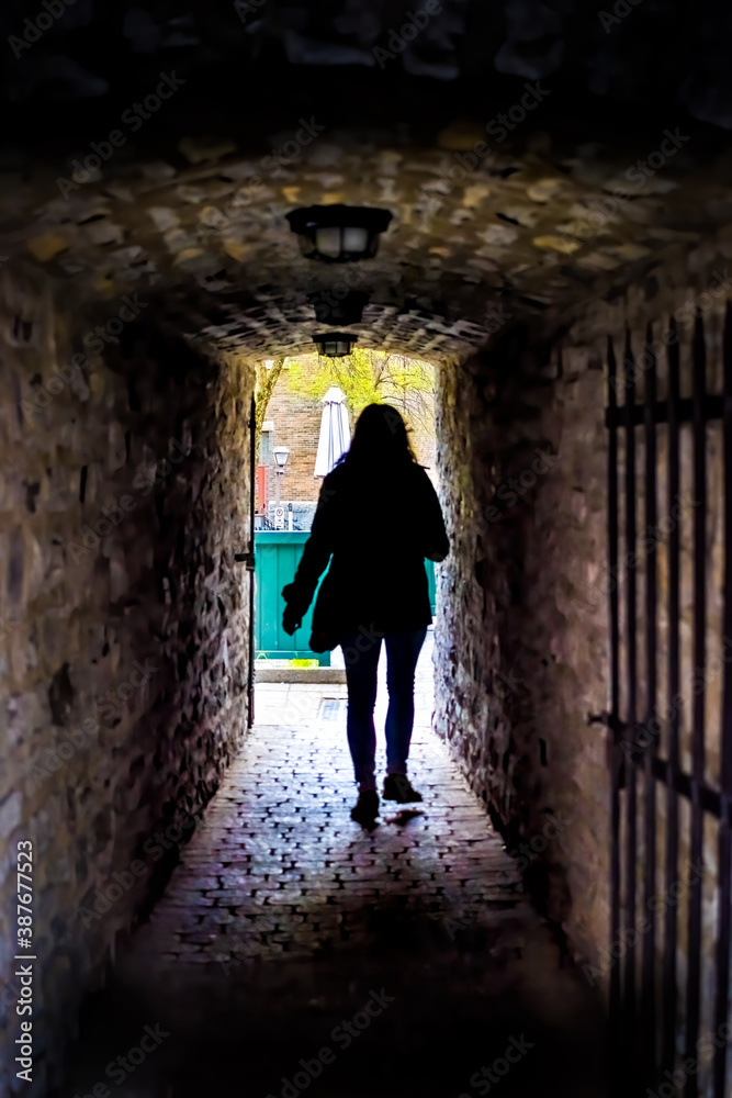 Silhouette of woman person tourist walking in Quebec City, Canada near Lower old town with cobblestone street narrow alley Passage De La Batterie with light lamp