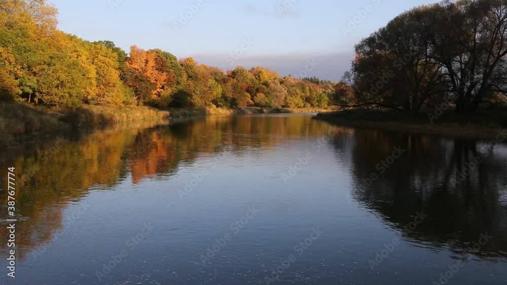 The sun rising on the autumn colored trees lining the Grand River. Shot in Waterloo, Ontario, Canada. The sun rising on the autumn colored trees lining the Grand River. Shot in Waterloo, Ontario, Canada.