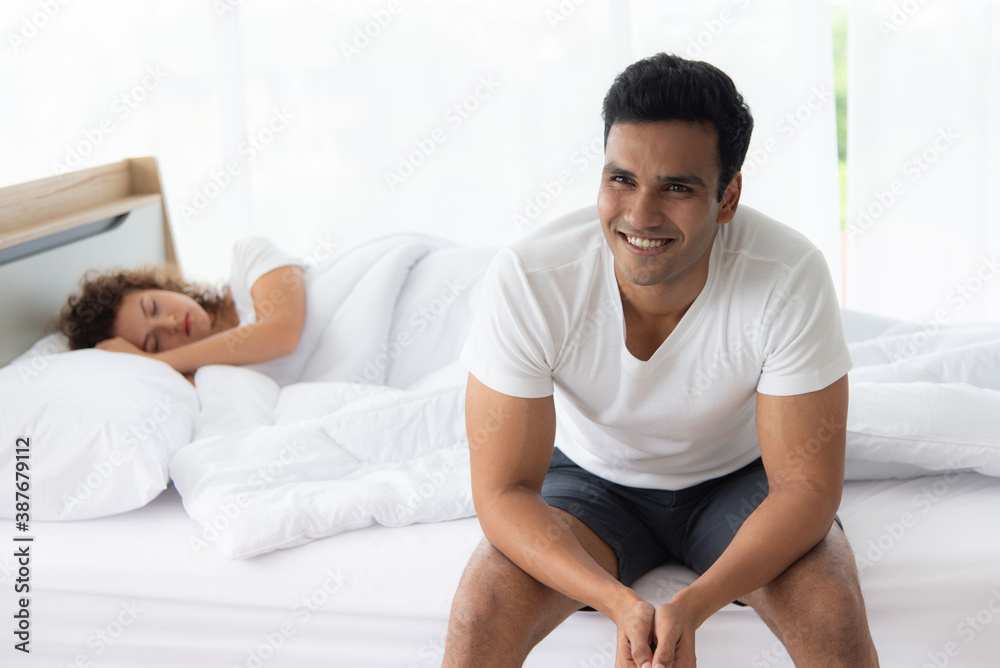 Family relation concept. Young attractive and smiling man relax on bed in the morning. The woman lying on bed cover with white blanklet. Family relation concept. Young attractive and smiling man relax on bed in the morning. The woman lying on bed cover with white blanklet.